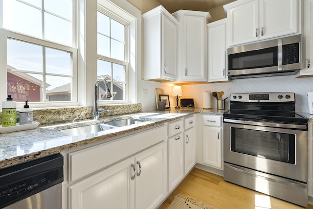 white kitchen with a black and white granite counter and stainless steal appliances